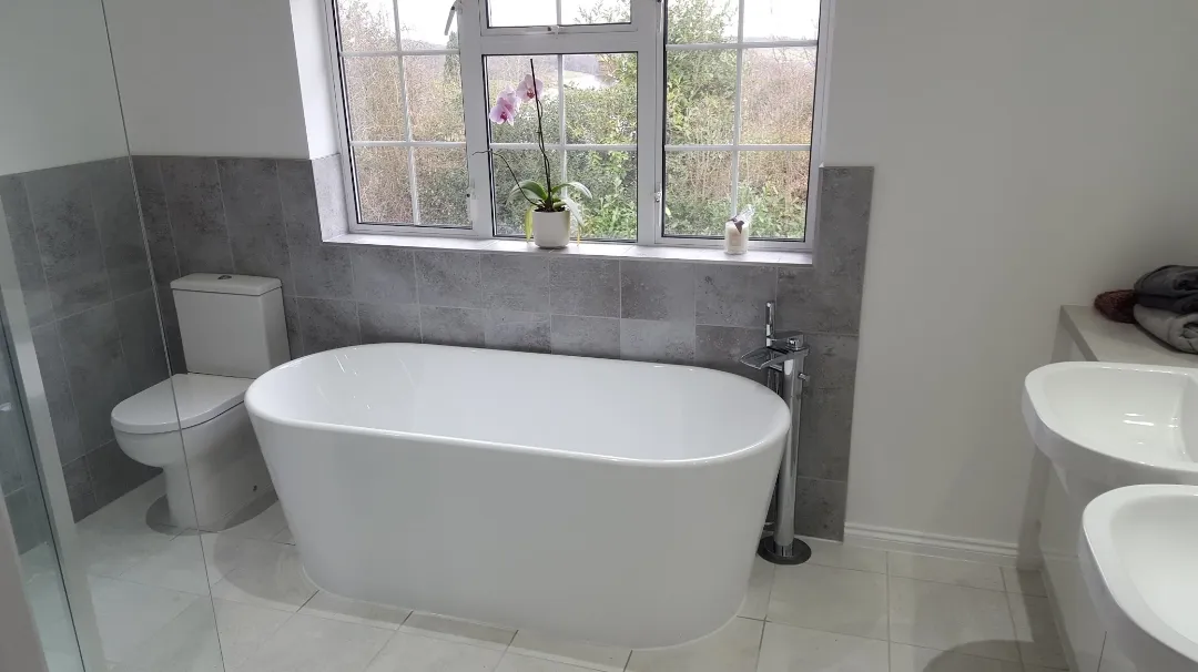 A white bath tub sitting under a bathroom window.