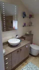 A bathroom with a toilet, sink and mirror.